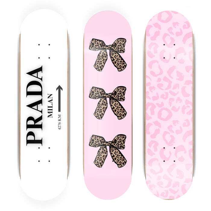 Three skateboard decks with Prada and pink designs on a white background